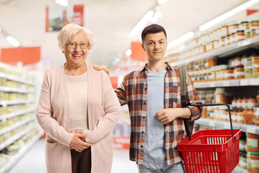 Jeune homme qui accompagne une personne âgée à l’épicerie.